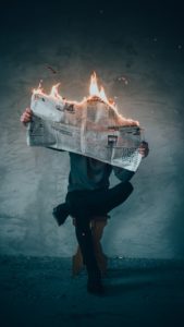Man holding burning newspaper